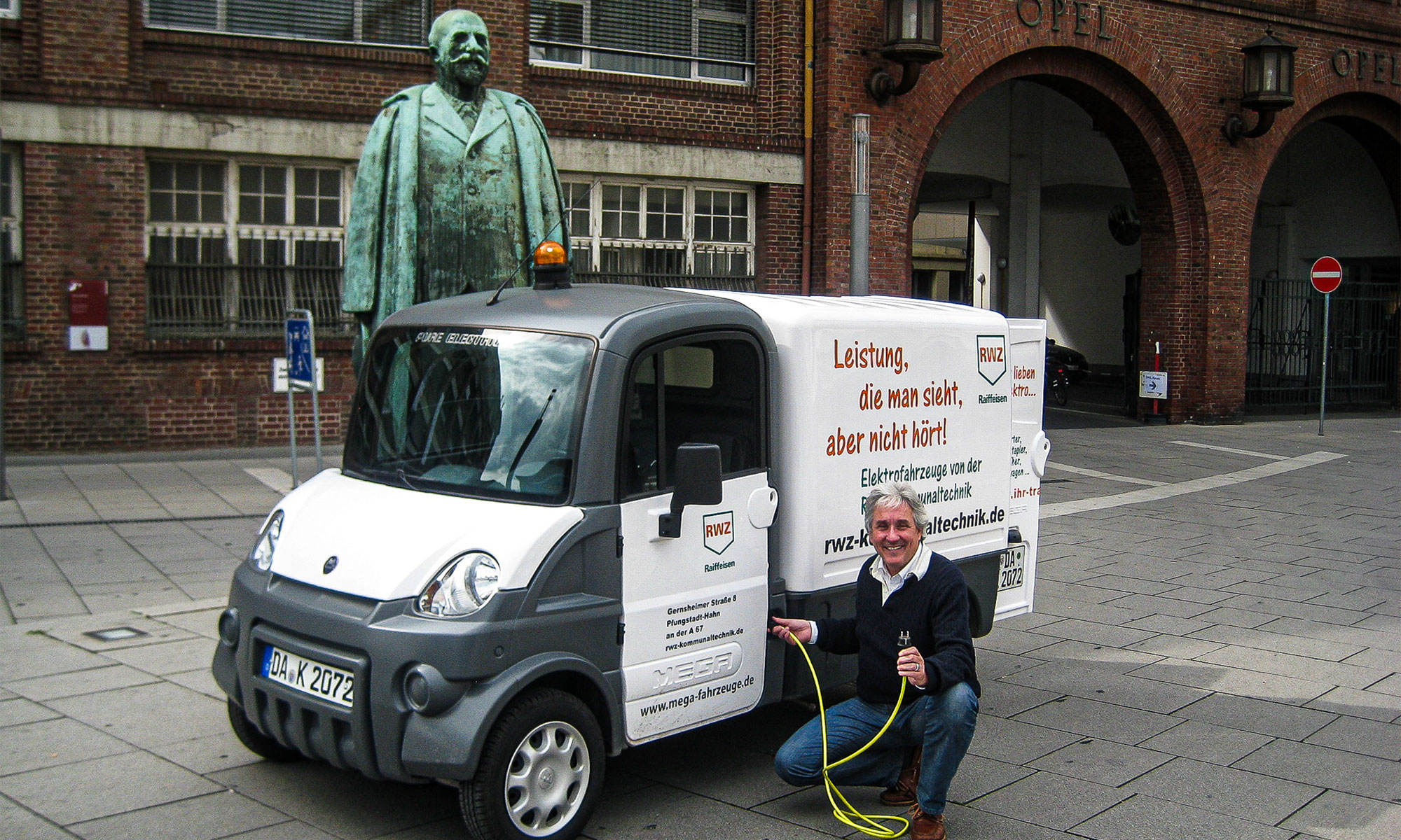 Achim Weidner 2010 beim Selbsttest der eMobilität in Rüsselsheim vor dem Opel-Hauptportal