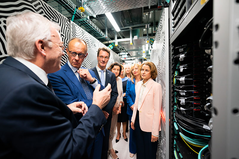 Bundeskanzler Friedrich Merz bei Erläuterungen zum Exascale-Rechner 'JUPITER' (Joint Undertaking Pioneer for Innovative and Transformative Exascale Research) durch Thomas Lippert, Direktor des Jülich Supercomputing Centre (JSC) im Rechenzentrum anlässlich seiner Einweihung im Forschungszentrum Jülich (3.v.l. Hendrik Wüst, nordrhein-westfälischer Ministerpräsident, 4.v.l. Dorothee Bär, Bundesministerin für Forschung, Technologie und Raumfahrt, v.r. Astrid Lambrecht, Vorstandsvorsitzende Forschungszentrum Jülich, Ekaterina Sachariewa, Kommissarin für Start-Ups, Forschung und Innovation der Europäischen Union). Foto: Bundesregierung/Steffen Kugler